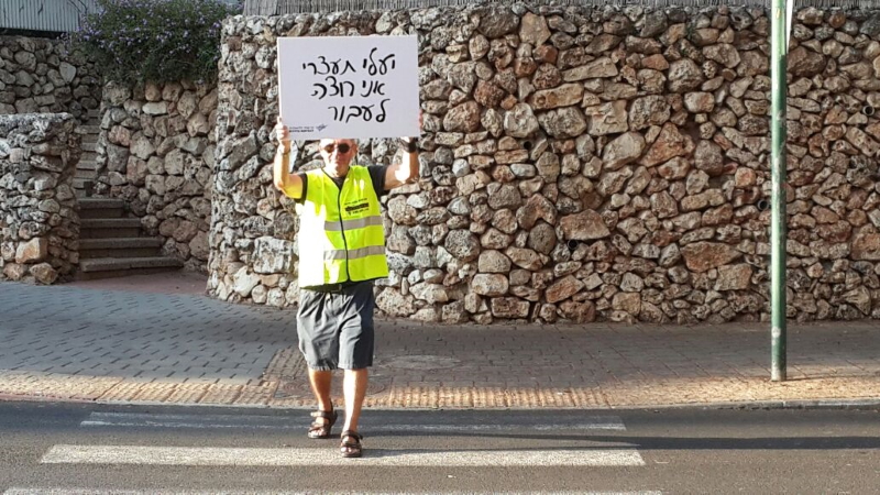 מעביר דרך בפעולה מחזיק שלט עם הכיתוב יעלי תעצרי אני רוצה לעבור