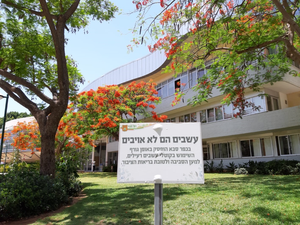 גינה בקריית ספיר עם שילוט המסביר על הפסקת השימוש בקוטלי עשבים בעיר