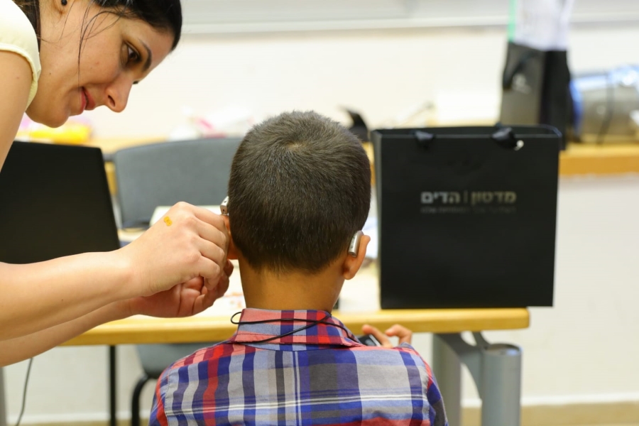 אשה מרכיבה מכשיר שמיעה לילד במהלך פסטיבל תרבות מונגשת 2019
