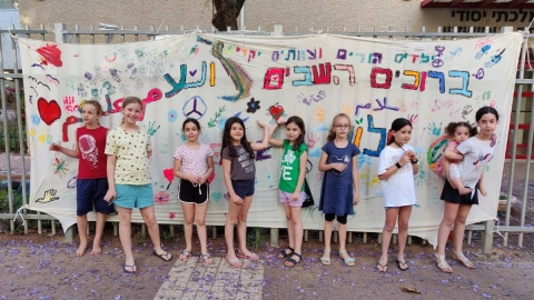 תלמידות אוסישקין לצד השלט ברוכים הבאים