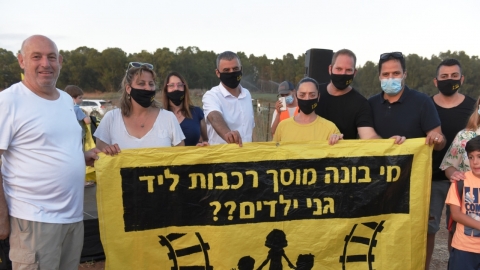 ראש העיר רפי סער מחזיק את שלט המחאה יחד עם חברת המועצה עדי לוי סקופ ומטה המאבק של ועד השכונה הירוקה