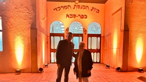 ראש העיר רפי סער ושורדת השואה הילדה מונין על רקע בית כנסת מואר בצהוב