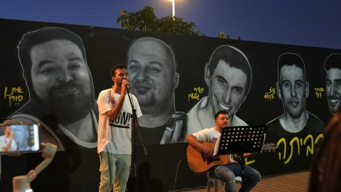 חבריו של אביתר דוד מכפר סבא מנגנים ושרים בחנוכת קיר דמויות החטופים תושבי העיר