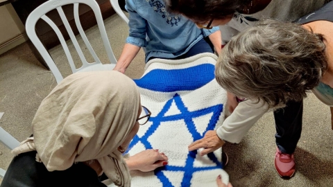 אזרחיות ותיקות בפעילות התנדבות של סריגת דגל מדינה ענק